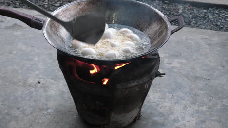 motion shot cooking duck eggs outdoors in hot oil on thai clay stove - traditional street food