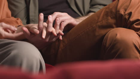 close up view of joined hands of a couple while they watching a movie in the cinema