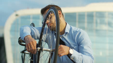 handsome man in business style riding a bicycle and stopping in front of the camera