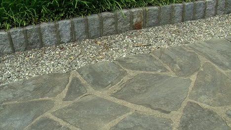 pan across a flagstone pathway with a border of pebbles and cobblestones