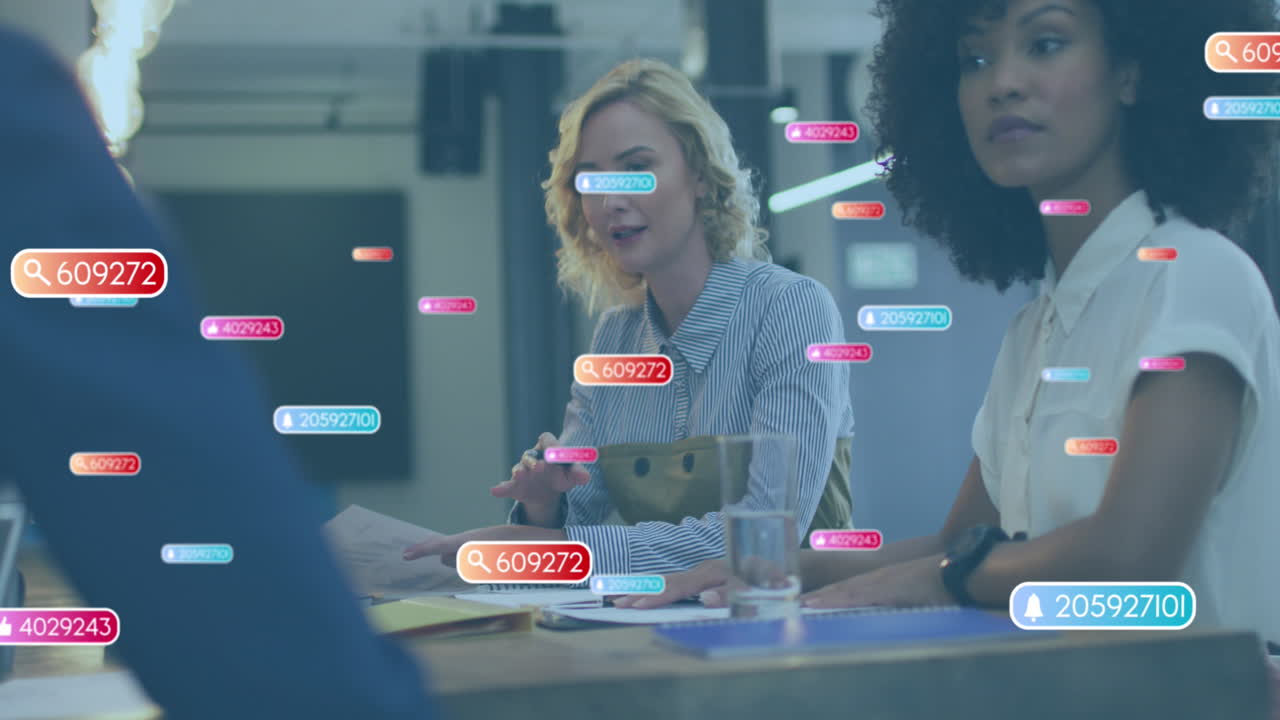 Animation of social media icons over caucasian woman talking to diverse colleagues at office