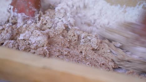 close shot of hands kneading homemade bread with whole wheat flour in a frugal wooden kitchen