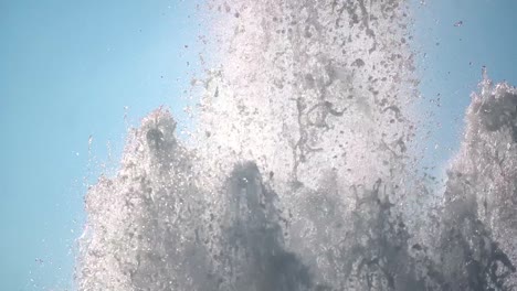 slow motion of water splashing from a large fountain on a light-blue sky, with beautiful drops and reflections.