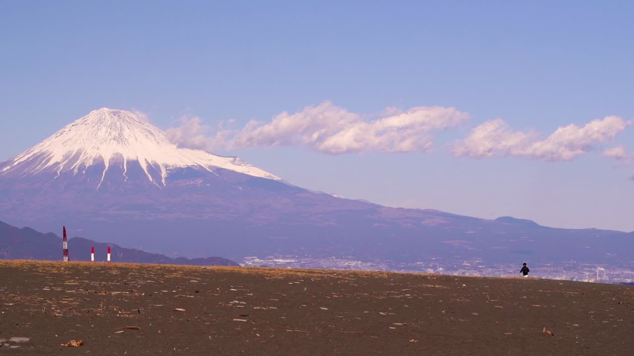 persona solitaria caminando en una playa abierta en japón con el monte fuji en segundo plano