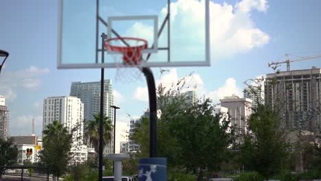 downtown cityscape business district skyscrapers in the distance panning across bokeh basketball court hoop foreground