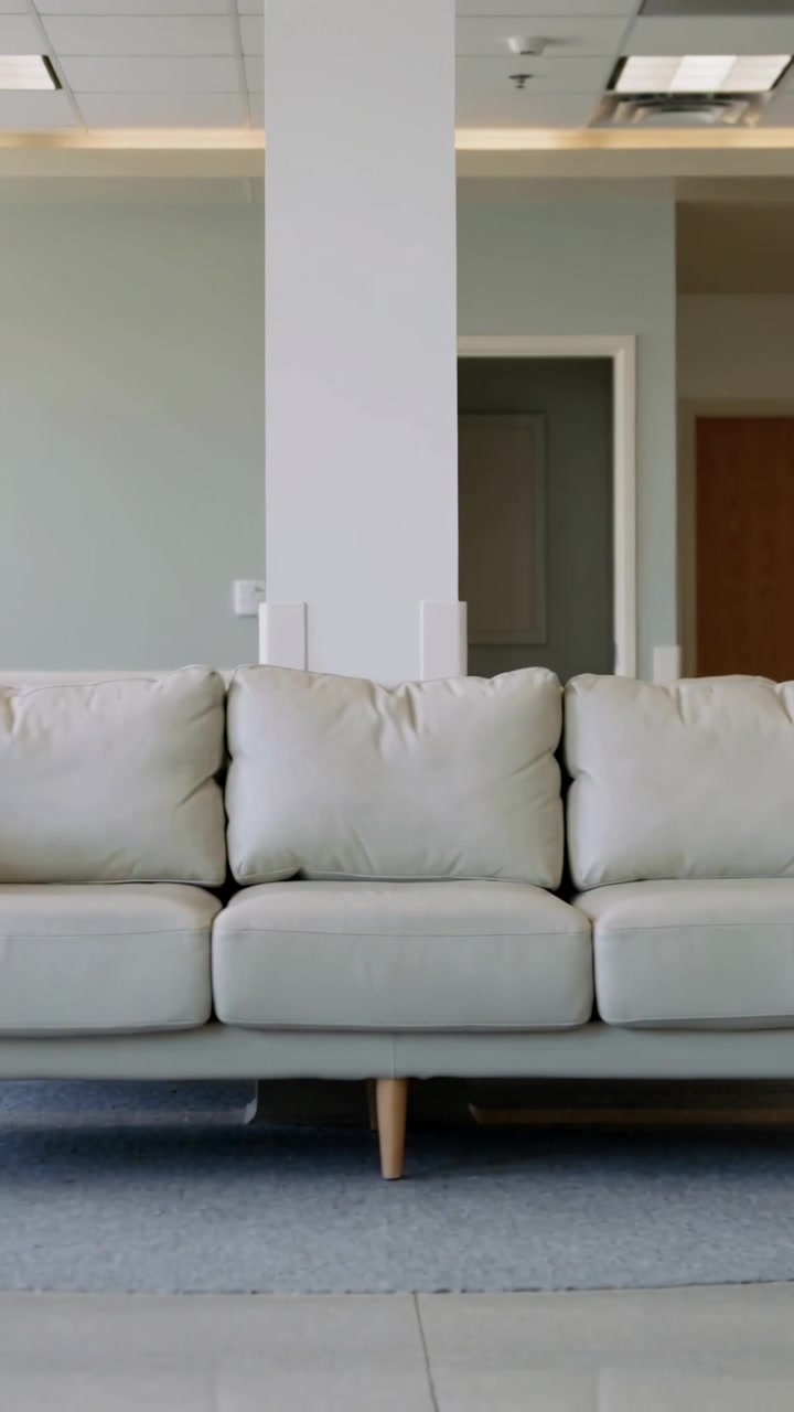 Vertical video: Sliding camera moving right, showing 3-seat cream sofa in lounge revealing column