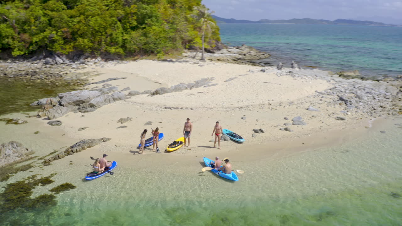 Aerial view of a group enjoying paddleboarding and kayaking on a tropical island beach