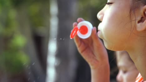 Close-up-of-schoolgirl-playing-with-bubble-wand-in-playground