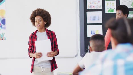 diversas maestras y escolares felices en los escritorios recitando en el aula de la escuela