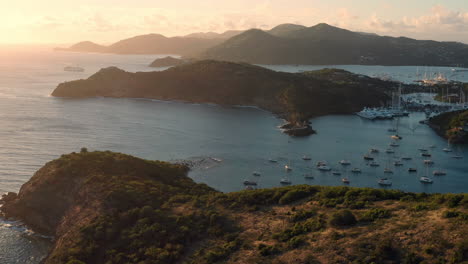 Toma-Aérea-De-La-Puesta-De-Sol-En-Puerto-Inglés-En-Antigua,-Caribe-Con-Vistas-De-Yates,-Veleros,-Puerto-Deportivo,-Bahía-Y-Acantilados