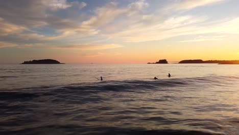 Surfers-enjoy-sunset-and-ocean-waves-off-Tofino-coast-on-Vancouver-Island