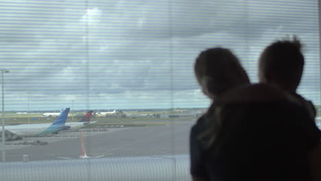 niño y madre mirando aviones a través de la ventana