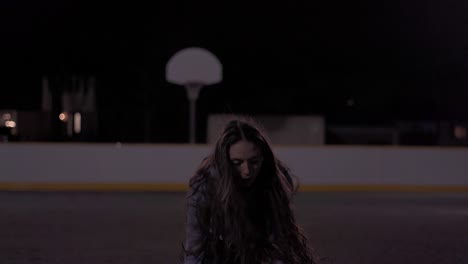 Action-shot-of-a-teenage-girl-dribbling-then-taking-a-shot-at-a-basketball-court-at-night-with-lights