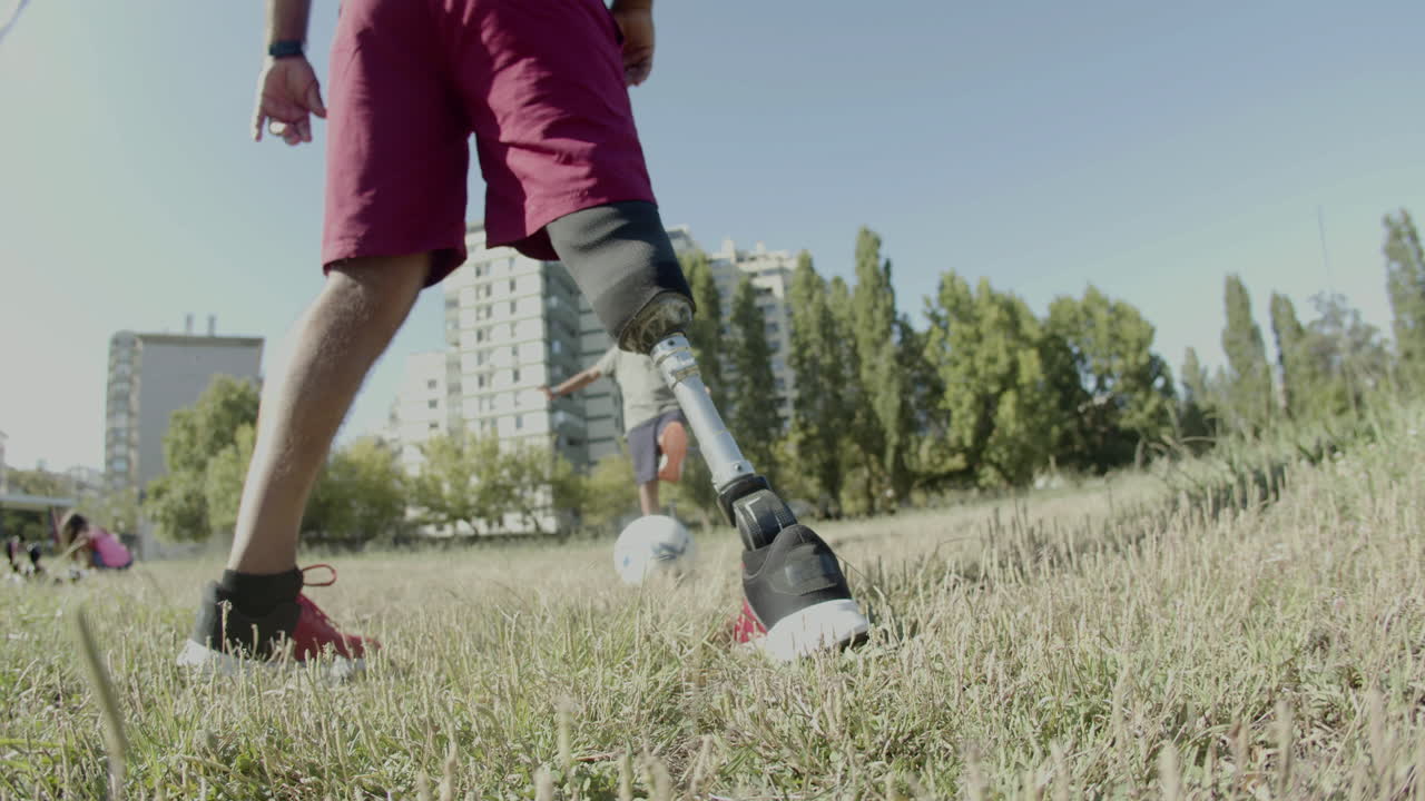 Close-up of mans prosthetic leg kicking ball around
