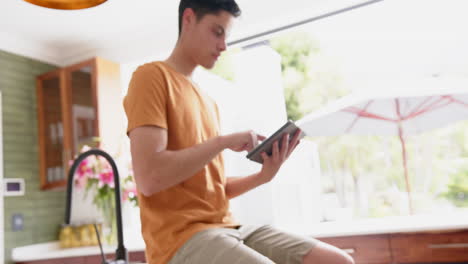 Thoughtful-biracial-man-using-tablet-by-door-to-sunny-garden,-copy-space,-slow-motion