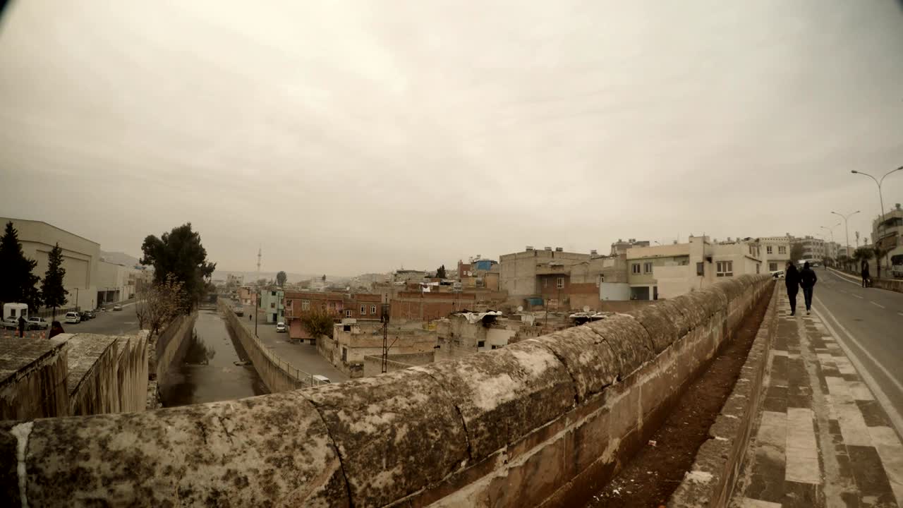 Ponte sul canale nel centro storico di Urfa, due uomini in lontananza, giornata nuvolosa e invernale a Urfa