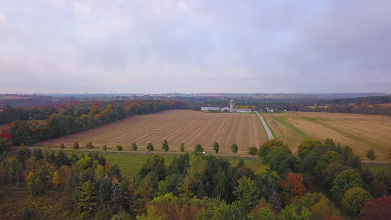 вид с воздуха, пролетающий над крышей амбара и открывающий живописные сельскохозяйственные угодья