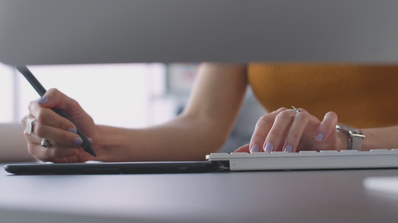 cerca de las manos de una arquitecta femenina en la oficina trabajando en una computadora de escritorio usando una tableta gráfica