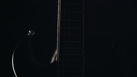 light slowly revealing guitar in complete darkness