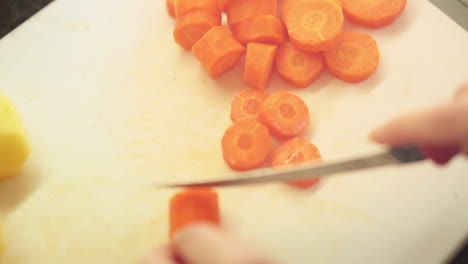 female hands slicing carrots in the kitchen cutting board