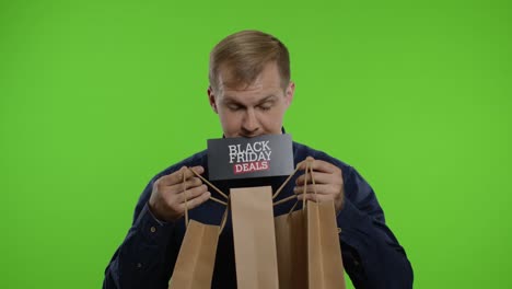 hombre sorprendido mostrando bolsas de compras y ofertas de black friday inscripción en su boca. llave de croma