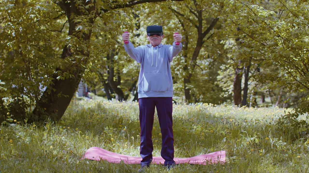 Senior man exercising, making dumbbell weight lifting exercises, wearing VR helmet play video game