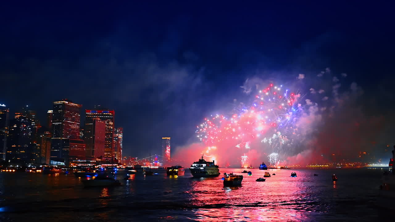 Water vehicles are standing still on the waterscape of the river in New York. Firework show is taking place over the water