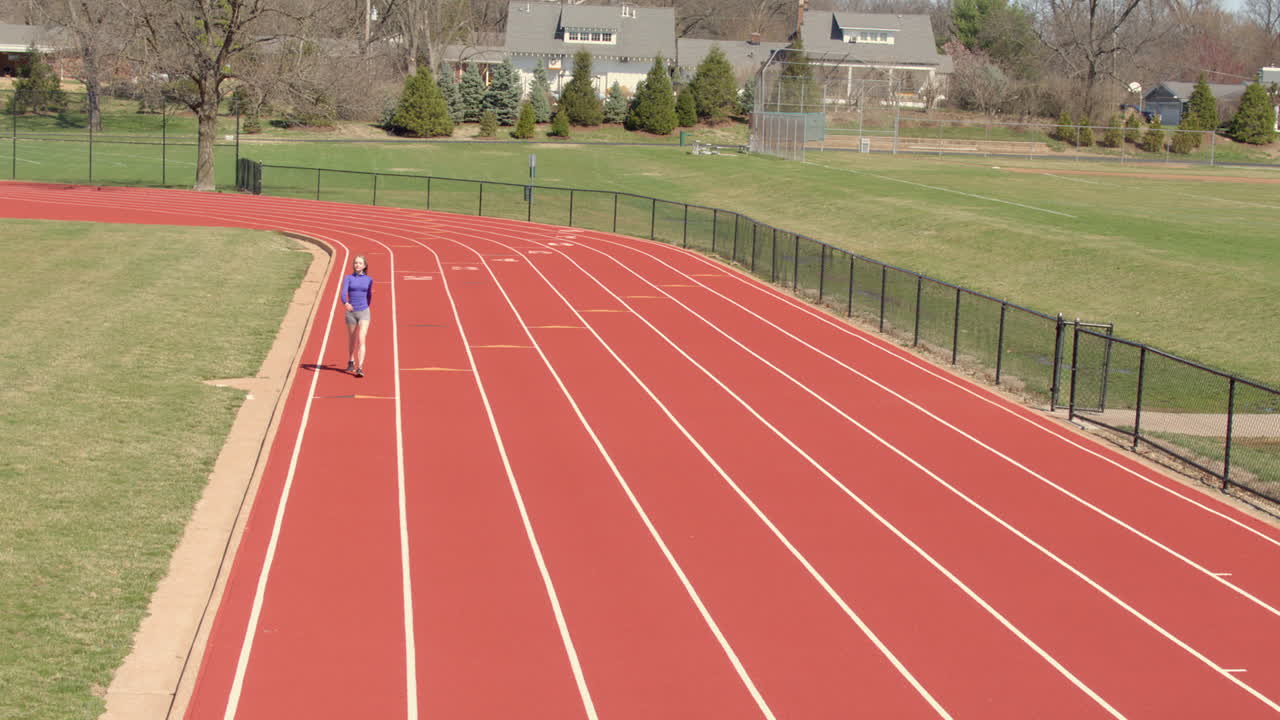 슬로우 모션으로 카메라를 향해 트랙을 걷고 있는 십대 소녀