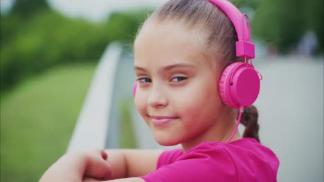 a young girl enjoys listening to music with stylish pink headphones amidst a scenic outdoor setting, radiating confidence and joy in every beat