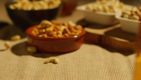 close up of hand choosing from bowls of cashews dry roasted peanuts and pistachio nuts in studio 4