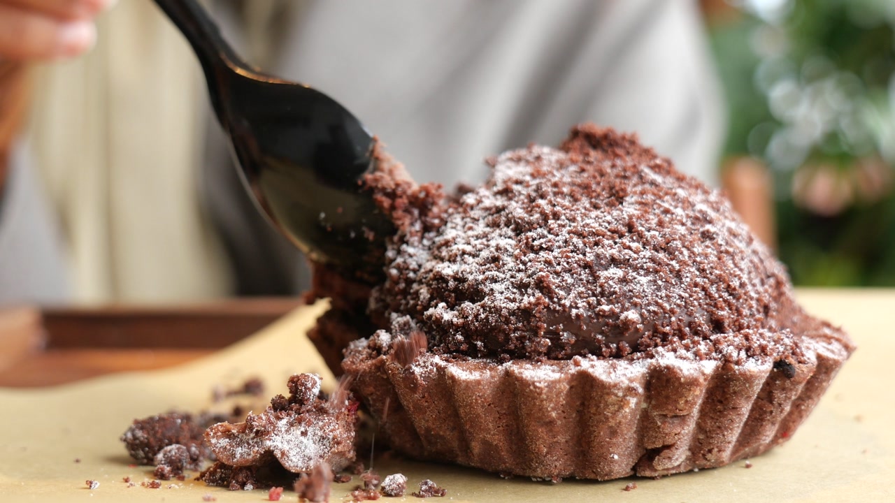 Close-up of a Hand Eating a Delicious Chocolate Tart with a Spoon
