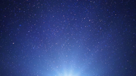 scintillating glitter particles falling rapidly against a deep blue gradient background with light rays - glowing particles create a magical and elegant effect, ideal for festive or cosmic themes