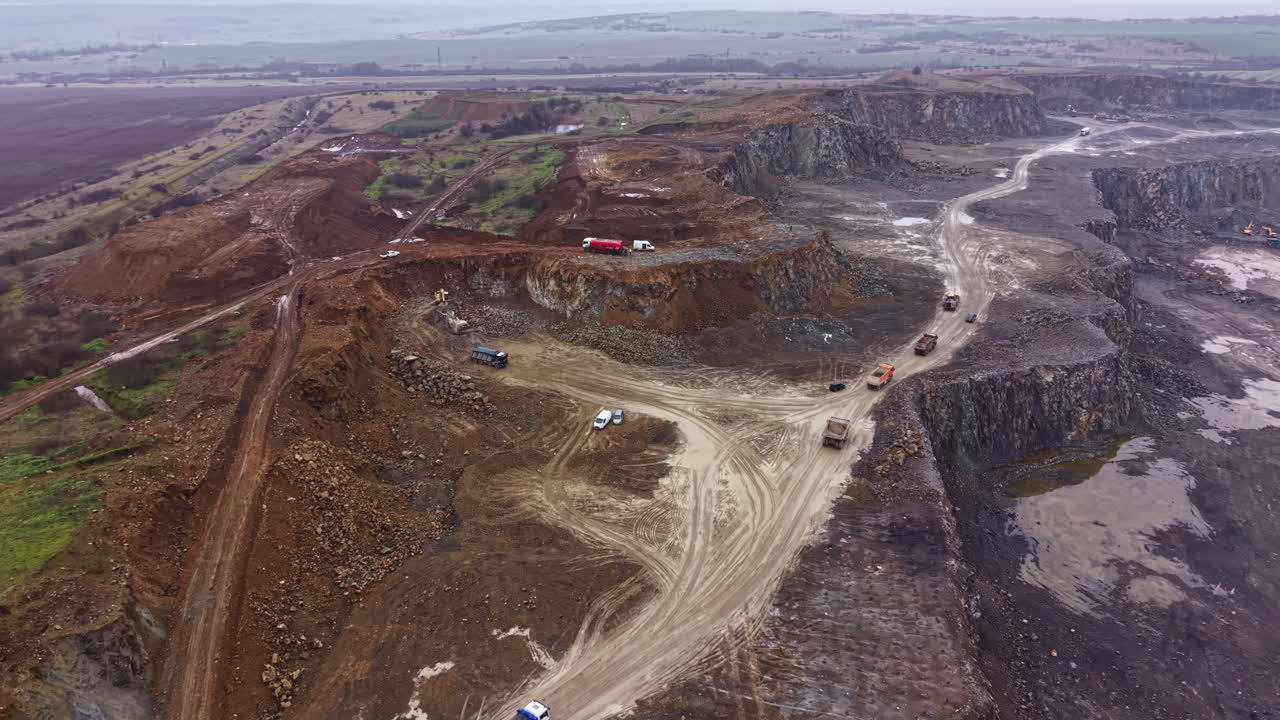 Granite quarry site with heavy machinery and workers in operation during daylight hours in a rural area