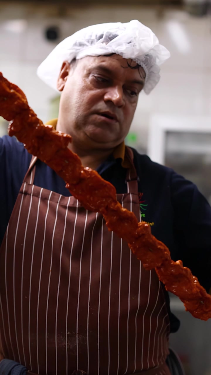 Chef che inserisce uno spiedino di carne marinata in un forno tandoor