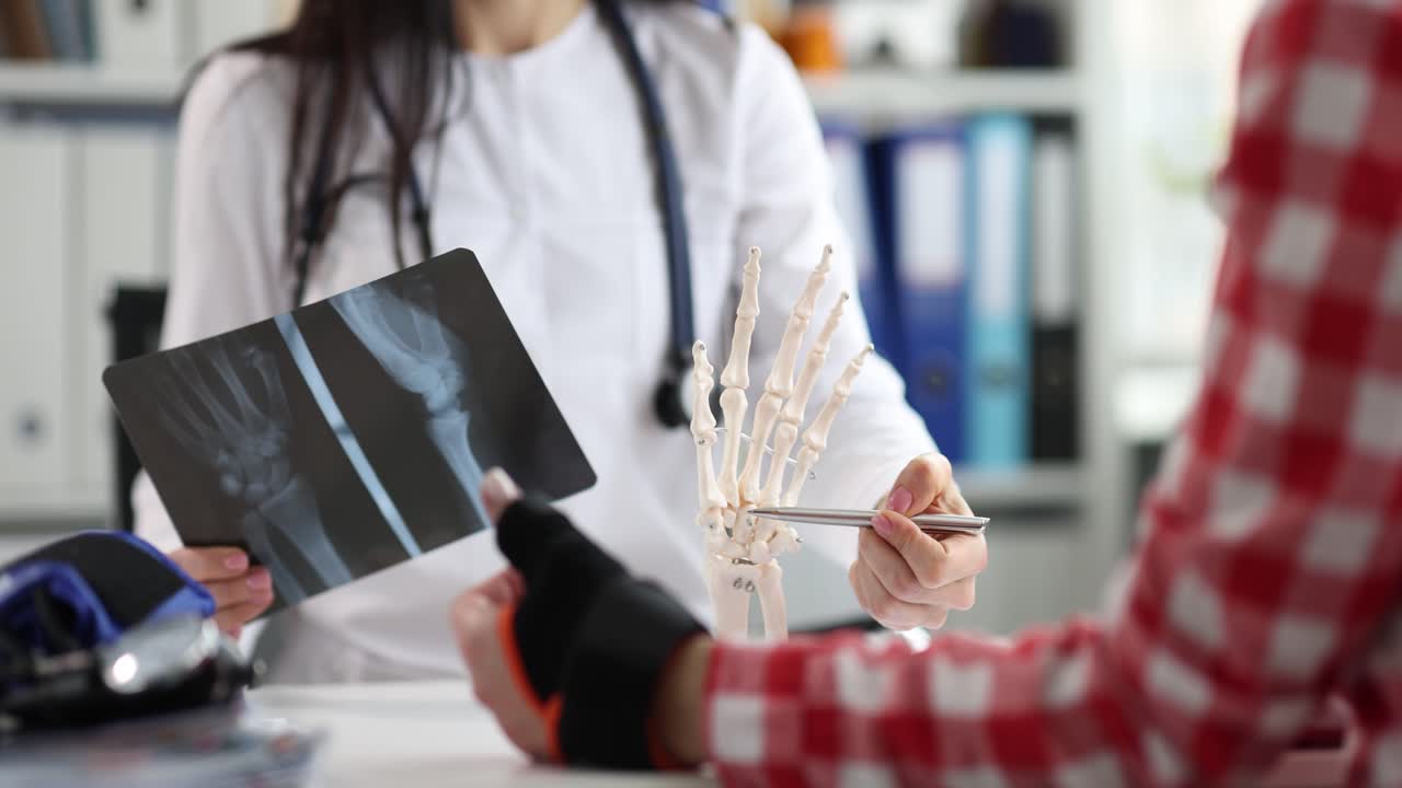 Doctor explaining wrist injury with X-ray and hand model