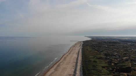 Aerial-view-of-the-North-Sea-shoreline-with-white-bath-houses-at-the-beach-outside-Løkken,-Denmark