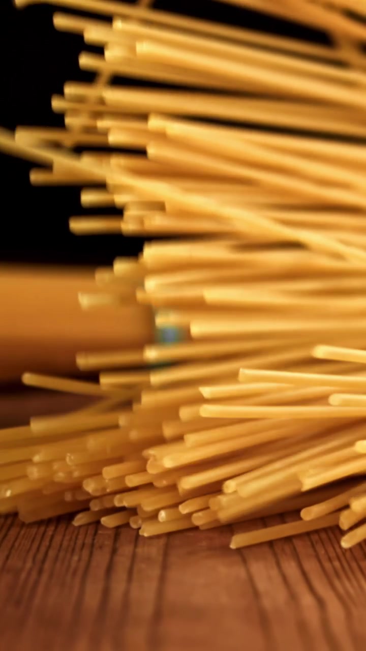 Spaghetti crudi che cadono su un tavolo di legno