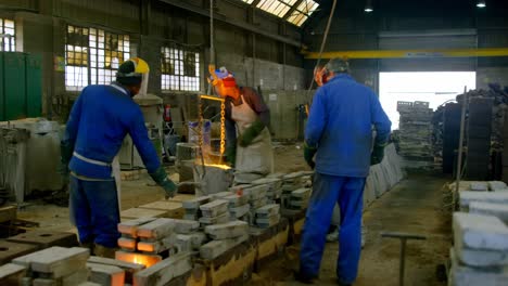 workers pouring molten metal in molds at workshop 4k