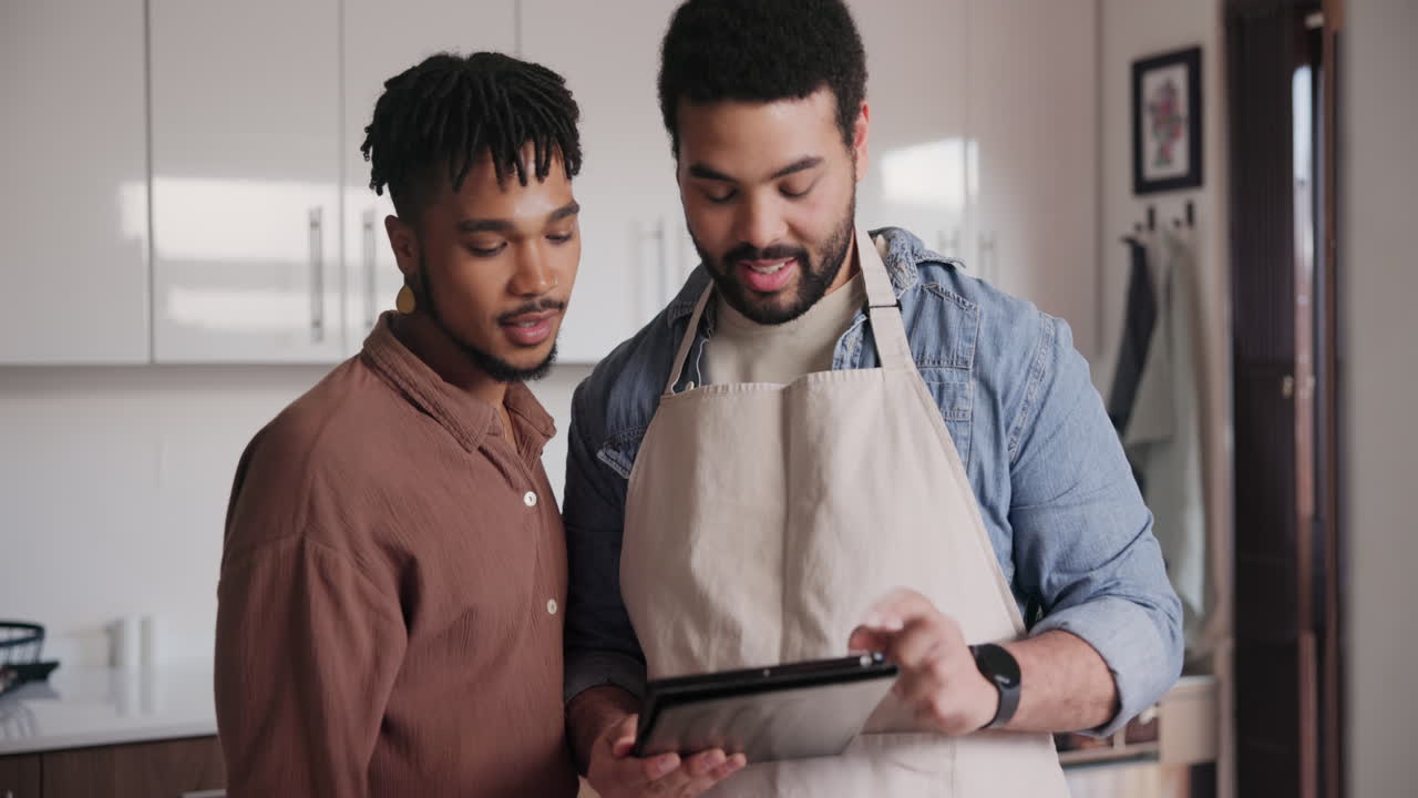 Two men looking at a tablet in the kitchen