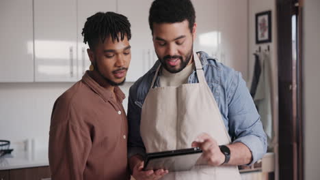 two men looking at a tablet in the kitchen