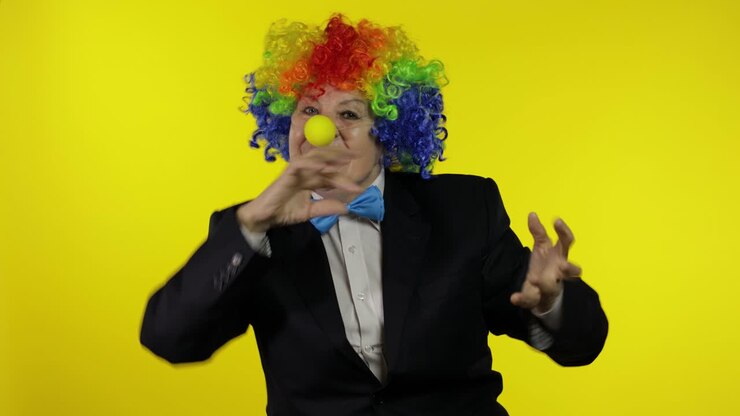 Anziana donna clown con parrucca che si diverte, sorride, balla, fa facce buffe.