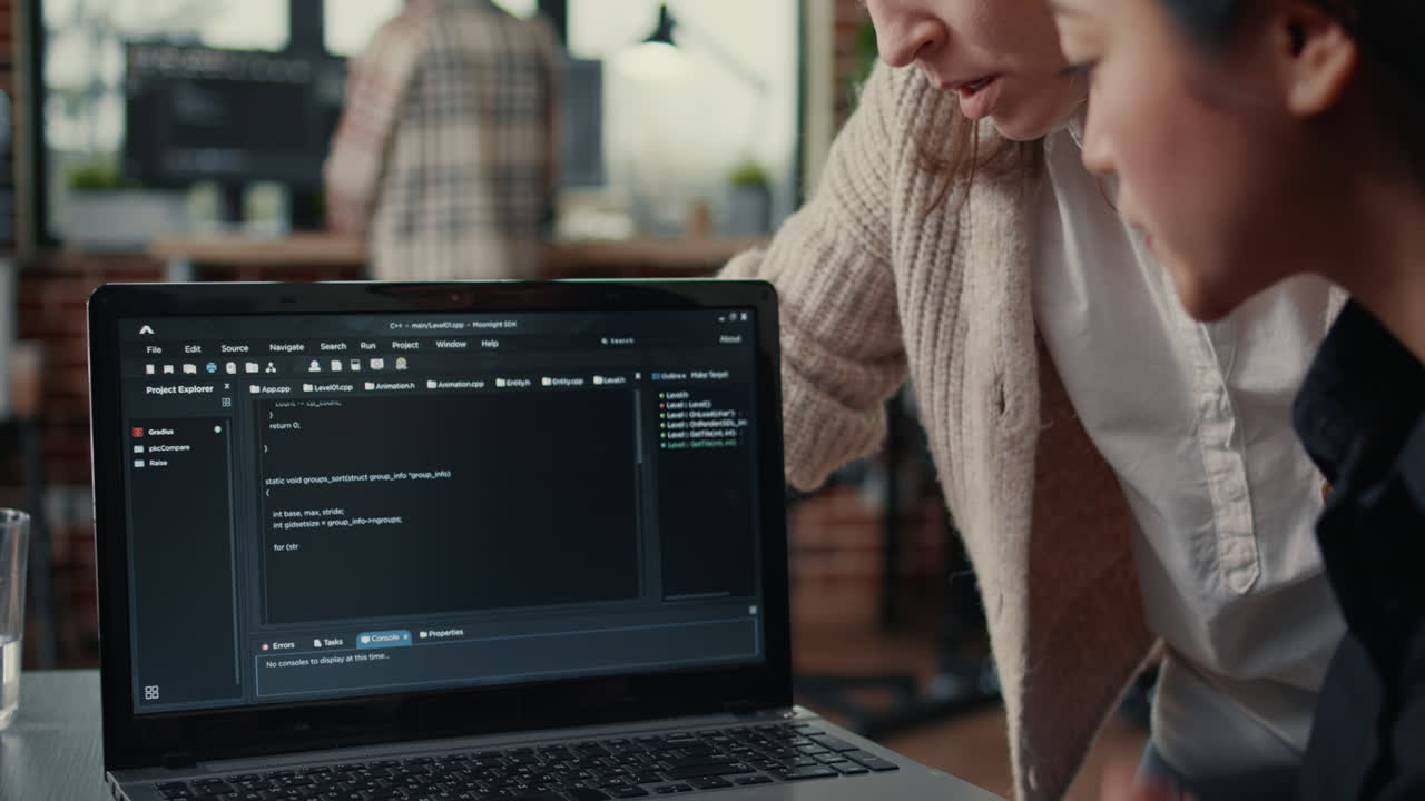 Team of software developers talking about source code running on laptop screen