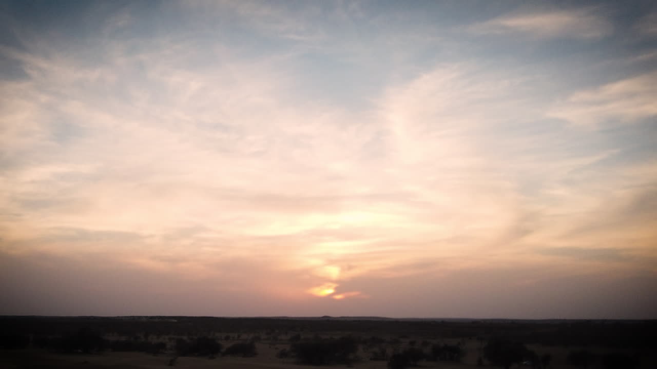 Dramatic desert sunset hyperlapse that zooms out and tilts up towards the sky.