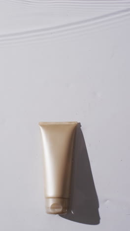 vertical video of beauty product tube in water with copy space on white background
