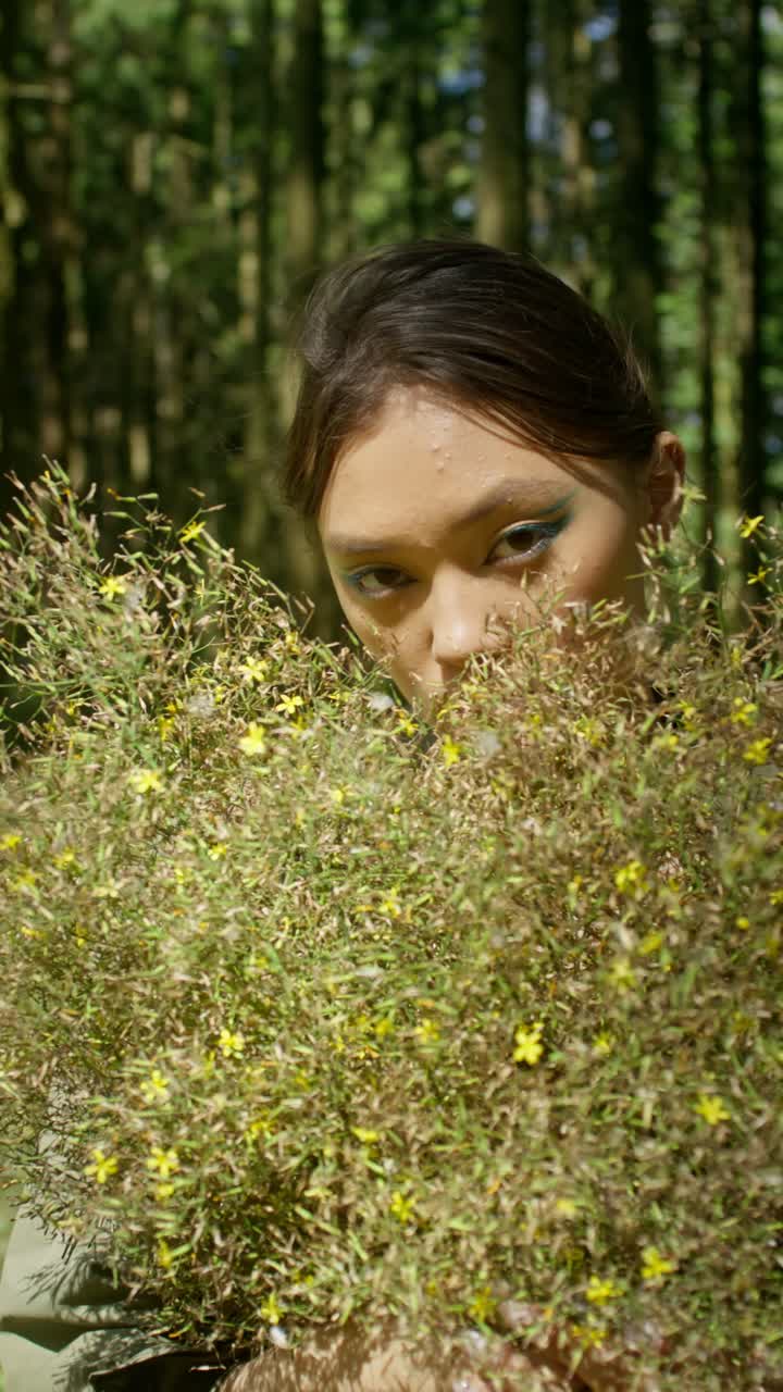A woman in nature among foliage and flowers