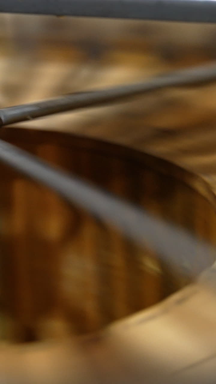 Frames with organic honey are rotated in the barrel-like centrifuge machine. Beekeepers extracting product from honey frames. Vertical video