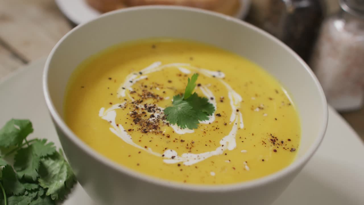 Video af cremet grøntsagssuppe i skål på træbord med dekorationer
