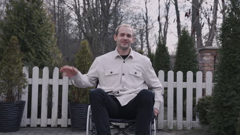 front view of a man in wheelchair waving at camera