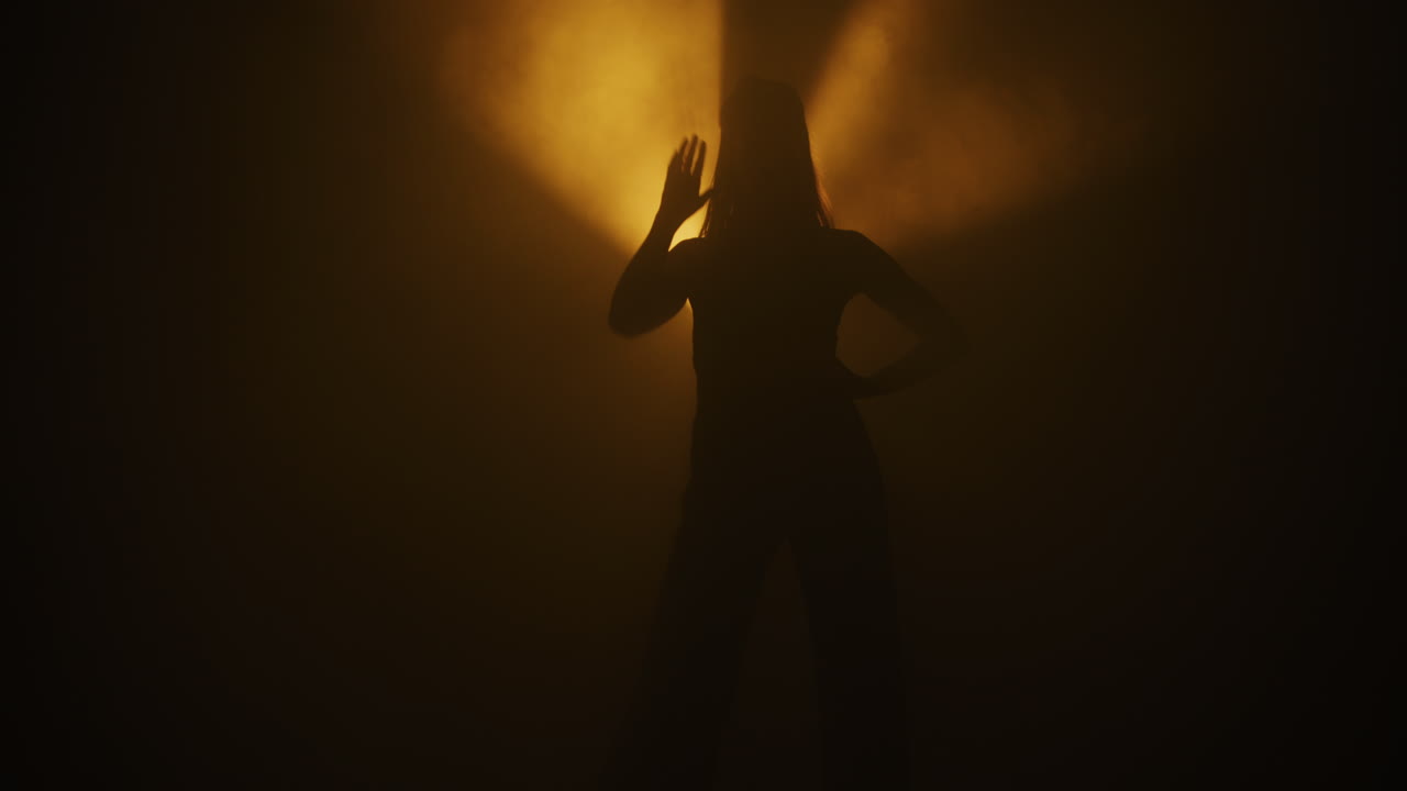 Silhouette of a Woman Dancing in a Smoky Studio