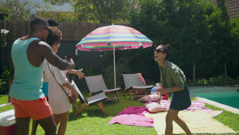 diverse friends setting up picnic area by pool with cooler and colorful towels
